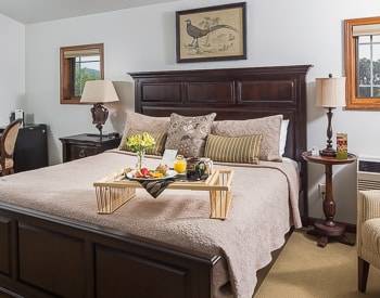 Dark wood head and footboard King bed With a tray with breakfast on it sitting on the bed, two night stands with lamps on each side of the bed